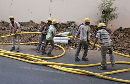 Labourers pull an electricity cable to be laid underground along a roadside in Ahmedabad, India, May 27, 2015. REUTERS/Shailesh Andrade