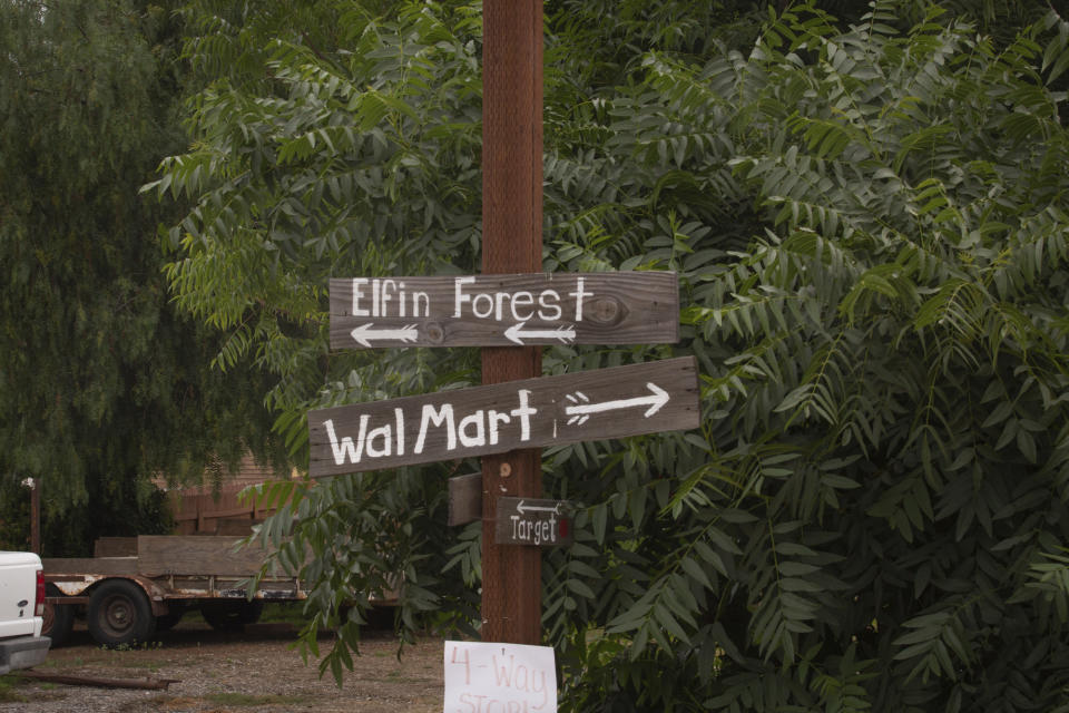In this June 30, 2019 photo, homemade signs are a tongue-in-cheek nod to years of tension among Elfin Forest, Harmony Grove and other rural communities in San Diego County, Calif. The town is accessed by a single winding two-lane road. When the valley catches fire, as it does periodically, that road is the only escape route. Residents will soon share it with 700 new neighbors. From coast to coast, homes continue to go up in floodplains and areas frequented by fire. Developments in disaster prone areas means big bucks for builders, but leaves homeowners in some communities at risk. (Kailey Broussard/News21 via AP)