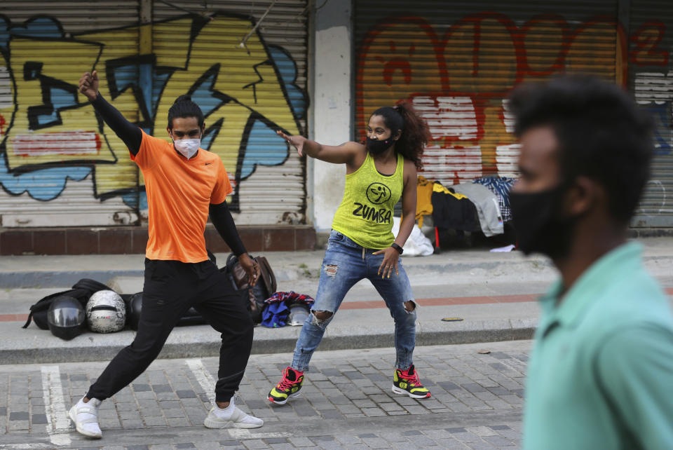 Artists wearing face masks as a precaution against the coronavirus perform on a street open to only pedestrians during weekends in Bengaluru, India, Saturday, Nov. 28, 2020. The project called Clean Air Street initiative was launched earlier this month and will run through February, 2021. India has more than 9 million cases of coronavirus, second behind the United States. (AP Photo/Aijaz Rahi)