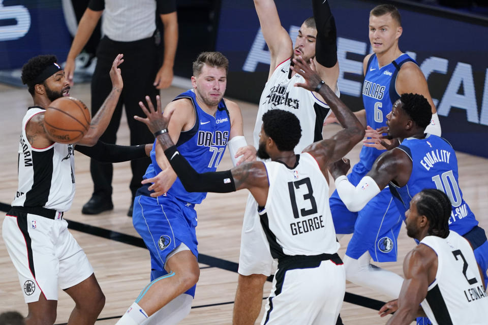 Dallas Mavericks' Luka Doncic (77) passes the ball out of a crowd during the second half of an NBA basketball first round playoff game against the Los Angeles Clippers Friday, Aug. 21, 2020, in Lake Buena Vista, Fla. (AP Photo/Ashley Landis, Pool)