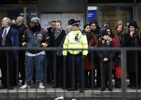 A police officer helps commuters to board buses during London Underground strikes at Kings Cross underground station in London February 6, 2014. REUTERS/Olivia Harris