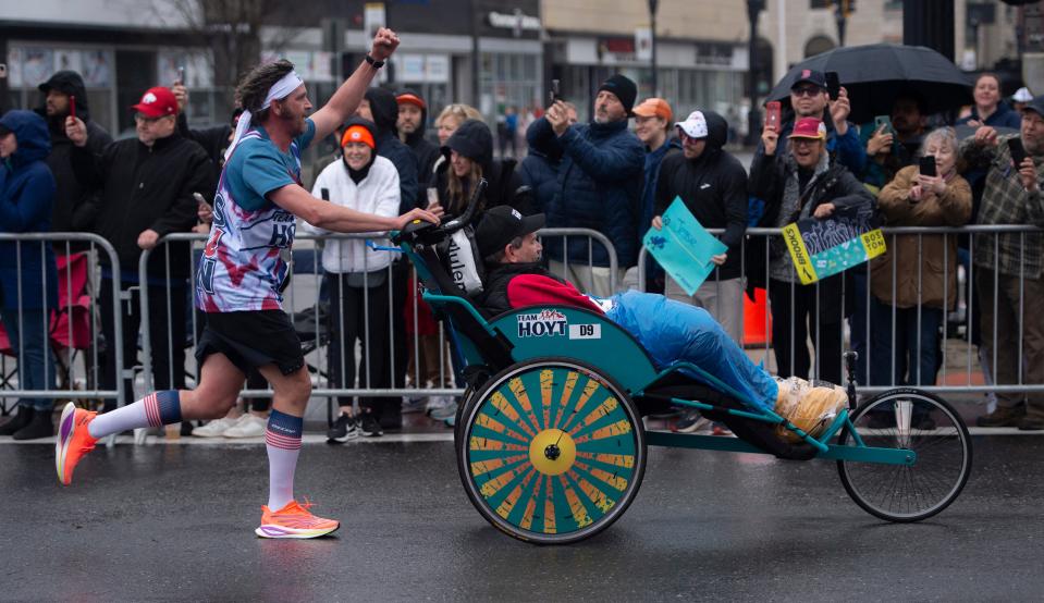 Danny and Brian Connolly react to the cheers of the crowd along Waverly Street in Framingham, during the 127th running of the Boston Marathon, April 17, 2023. 