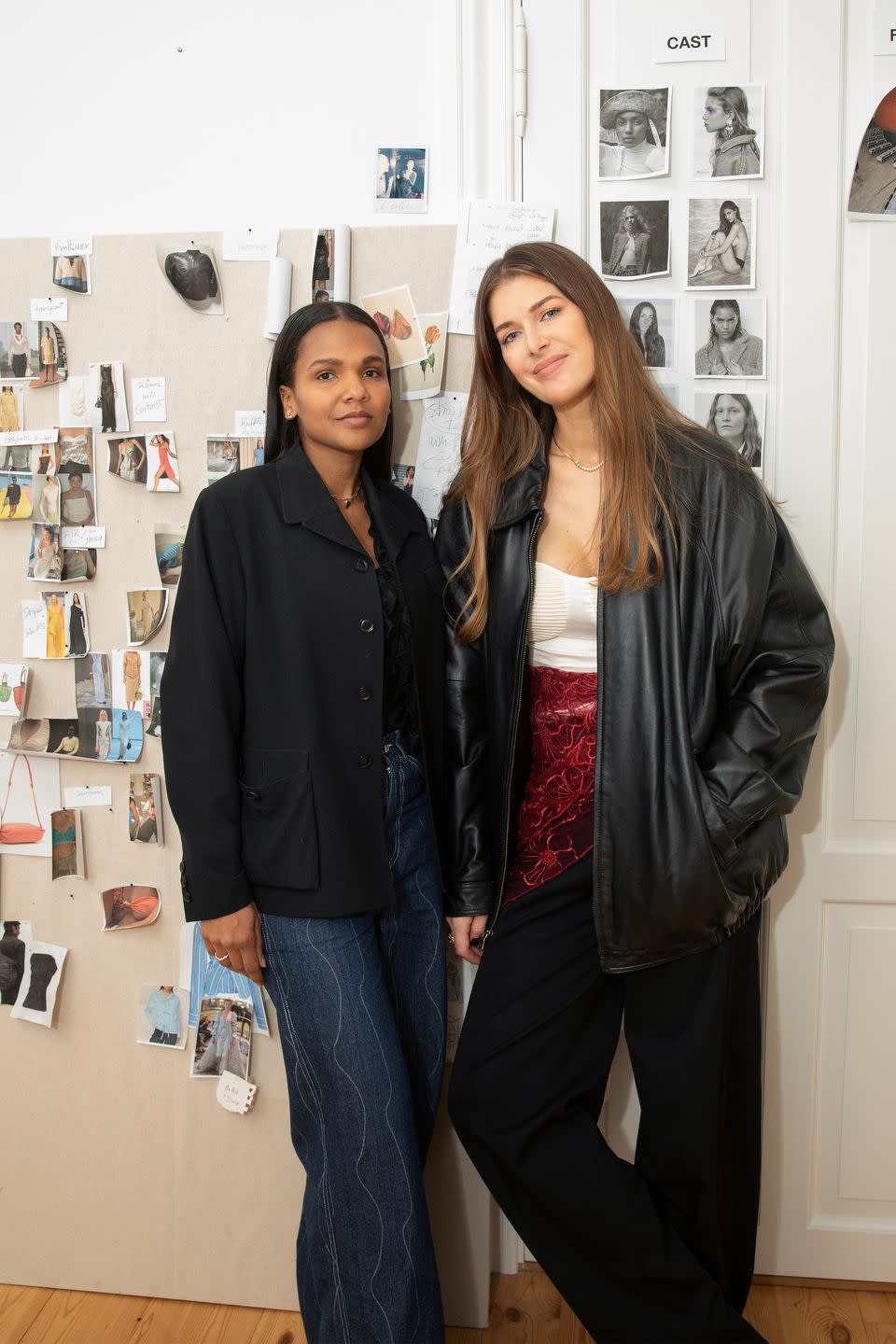 two women stand in front of a wall of photos