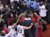 Toronto Raptors forward Kawhi Leonard, center, reacts with teammates after making the game-winning shot as Philadelphia 76ers center Joel Embiid (21) walks away at the end of an NBA Eastern Conference semifinal basketball game, in Toronto, Sunday, May 12, 2019. (Nathan Denette/The Canadian Press via AP)