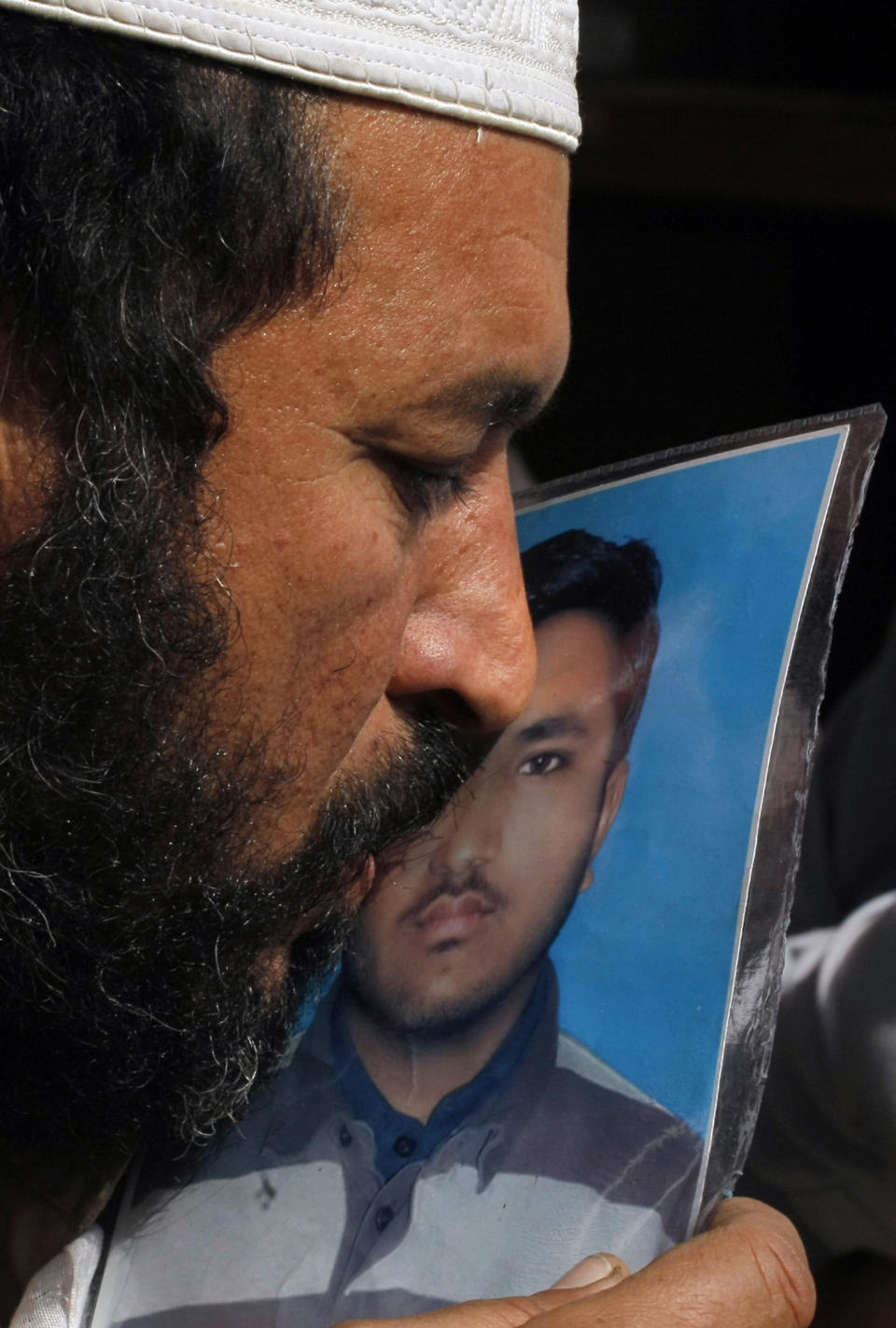 In this Jan. 28, 2014 photo, Pakistani Mohammad Wasil, kisses a photograph of his 19-year-old son, Hilal, a polio worker who was killed by militants, at his home in Peshawar, Pakistan. Pakistan’s beleaguered battle to eradicate polio is threatening a global, multi-billion dollar campaign to wipe out the disease worldwide. Because of Pakistan, the virus is spreading to countries that were previously polio free, say U.N. officials. (AP Photo/Mohammad Sajjad)