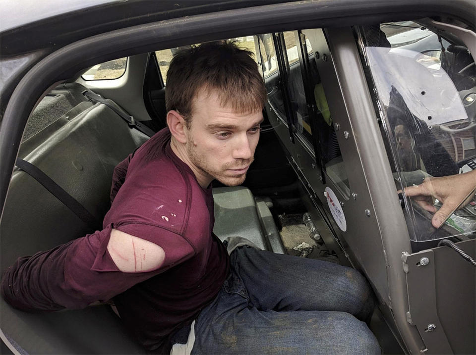 <p>In this image released by the Metro Nashville Police Department, Travis Reinking sits in a police vehicle after being apprehended in a wooded area in Nashville, Tenn., on Monday, April 23, 2018. Reinking, 29, the suspect in a quadruple homicide at a Nashville Waffle House was taken into custody Monday, police said. More than 100 Nashville police officers had been going door-to-door and searching wooded areas, joined by dozens of agents with the FBI, the U.S. Bureau of Alcohol, Tobacco, Firearms and Explosives and troopers with the Tennessee Highway Patrol. (Metro Nashville Police Department via AP) </p>