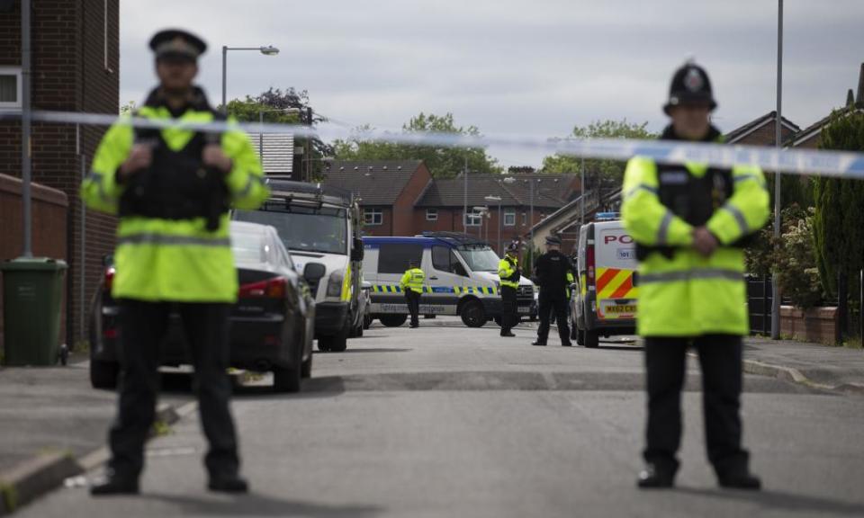 Police officers guard the entrance to a street in Moss Side where raids took place on Sunday.