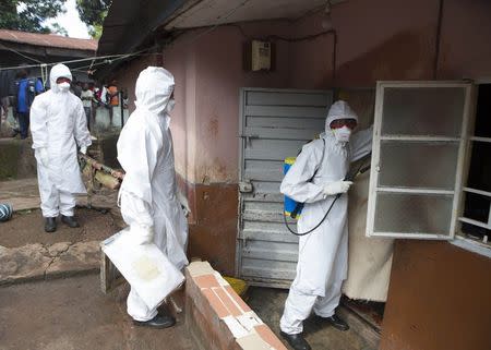 A burial team wearing protective clothing, prepare to enter the home a person suspected of having died of the Ebola virus, in Freetown September 28, 2014. REUTERS/Christopher Black/WHO/Handout via Reuters