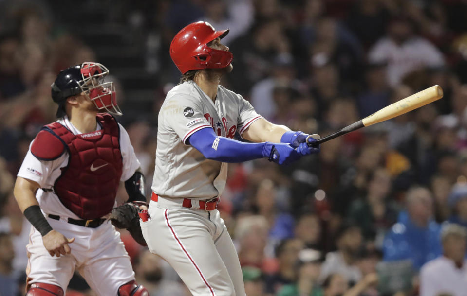Philadelphia Phillies right fielder Bryce Harper, right, watches the flight of his two run home run in the fifth inning during a baseball game against the Boston Red Sox at Fenway Park in Boston, Wednesday, Aug. 21, 2019. At left is Boston Red Sox catcher Christian Vazquez. (AP Photo/Charles Krupa)
