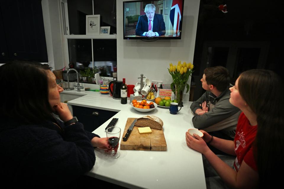 Members of a family listen as Britain's Prime Minister Boris Johnson makes a televised address to the nation from inside 10 Downing Street in London, with the latest instructions to stay at home to help contain the Covid-19 pandemic, from a house in Liverpool, north west England on March 23, 2020. - Britain on Monday ordered a three-week lockdown to tackle the spread of coronavirus, shutting "non-essential" shops and services, and banning gatherings of more than two people. "Stay at home," Prime Minister Boris Johnson said in a televised address to the nation, as he unveiled unprecedented peacetime measures after the death toll climbed to 335. (Photo by Paul ELLIS / AFP) (Photo by PAUL ELLIS/AFP via Getty Images)