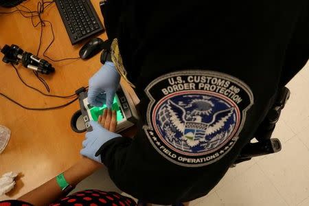 A woman who is seeking asylum has her fingerprints taken by a U.S. Customs and Border patrol officer at a pedestrian port of entry from Mexico to the United States, in McAllen, Texas, U.S., May 10, 2017. REUTERS/Carlos Barria/Files