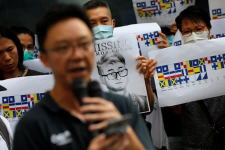 A demonstrator holds a poster of Simon Cheng as he and others shout slogans during a protest outside the British Consulate-general office in Hong Kong