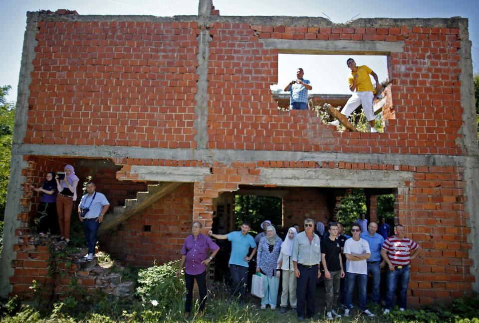 Bosnian Muslims watch a mass funeral from a war-torn house in the village of Biscani, near Prijedor July 20, 2014. (REUTERS/Dado Ruvic)