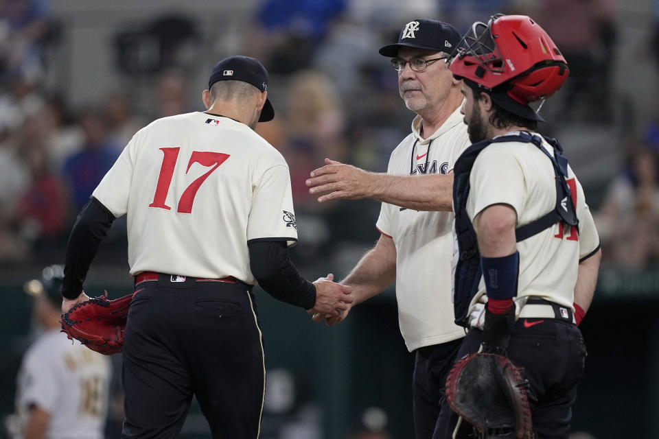 Texas Rangers starting pitcher Nathan Eovaldi (17) turns the ball over to manager Bruce Bochy, center, as catcher Austin Hedges (11) stands by on the mound in the third inning of a baseball game against the Oakland Athletics, Saturday, Sept. 9, 2023, in Arlington, Texas. (AP Photo/Tony Gutierrez)