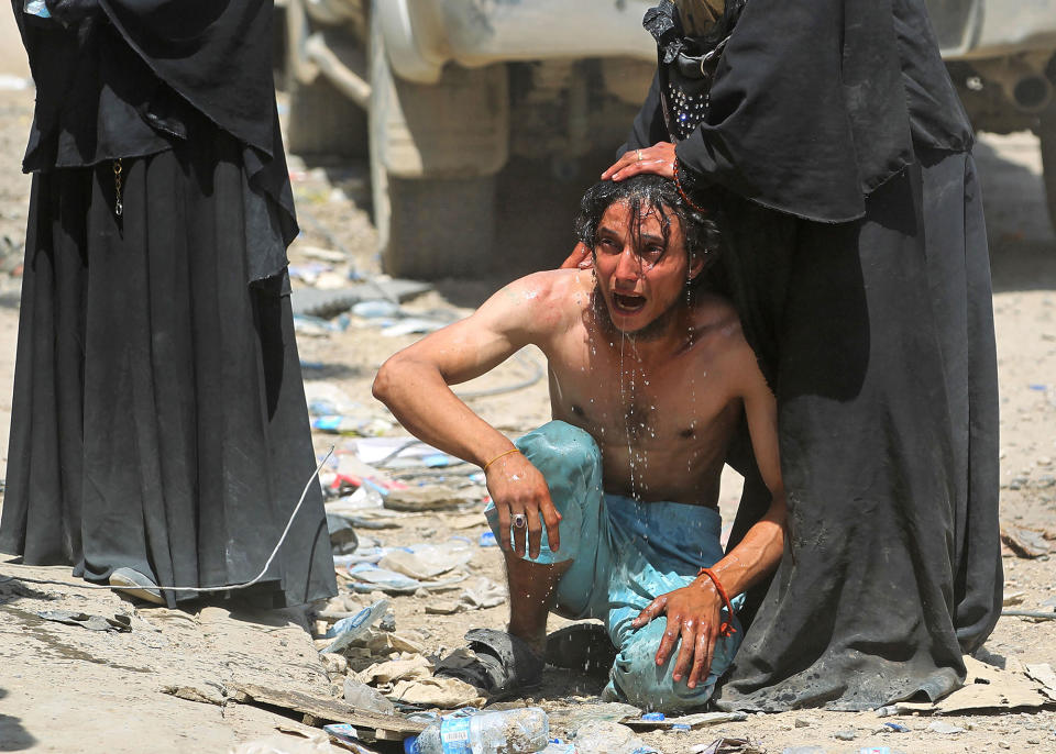 <p>An Iraqi woman pours water to calm down a civilian, who witnessed a suicide attack as people were escaping the Old City of Mosul, as he cries on June 23, 2017.<br> (Photo: Ahmad al-Rubaye/AFP/Getty Images) </p>