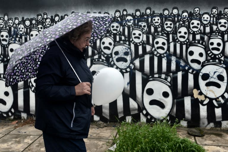 A woman contemplates artwork representing concentration camp prisoners at the old railway station in Thessaloniki