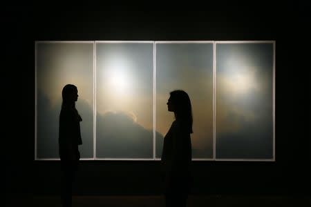 Christie's assistants pose for photographers with Gerhard Richter's "Wolken (Fenster)" at Christie's auction house in London September 22, 2014. REUTERS/Stefan Wermuth