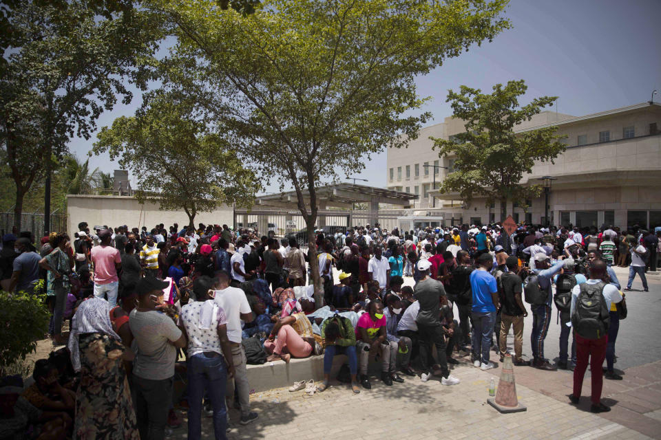 People gather in front of the U.S. Embassy in Port-au-Prince, Haiti, Friday, July 9, 2021. A large crowd gathered outside the embassy amid rumors on radio and social media that the U.S. will be handing out exile and humanitarian visas, two days after Haitian President Jovenel Moïse was assassinated in his home. (AP Photo/Joseph Odelyn)