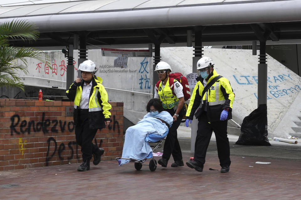 Medical workers escort a protester from Hong Kong Polytechnic University in Hong Kong, Wednesday, Nov. 20, 2019. A small band of anti-government protesters, their numbers diminished by surrenders and failed escape attempts, remained holed up at a Hong Kong university early Wednesday as they braced for the endgame in a police siege of the campus. (AP Photo/Vincent Yu)