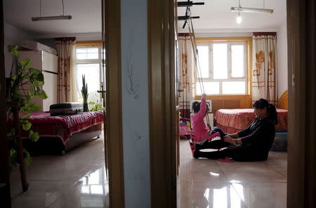 Huang Peiyao, 54, plays with her adopted daughter in a room that was used by her dead son, while a suitcase containing a picture of her son is seen in another room, during an interview in her house in Zhangjiakou, China, November 22, 2015. REUTERS/Kim Kyung-Hoon