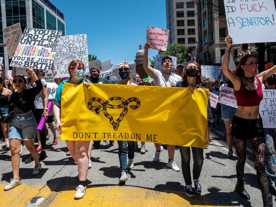 Protesters hold up signs as they march down Congress Ave at a protest outside the Texas state capitol on May 29, 2021 in Austin, Texas (Getty Images)