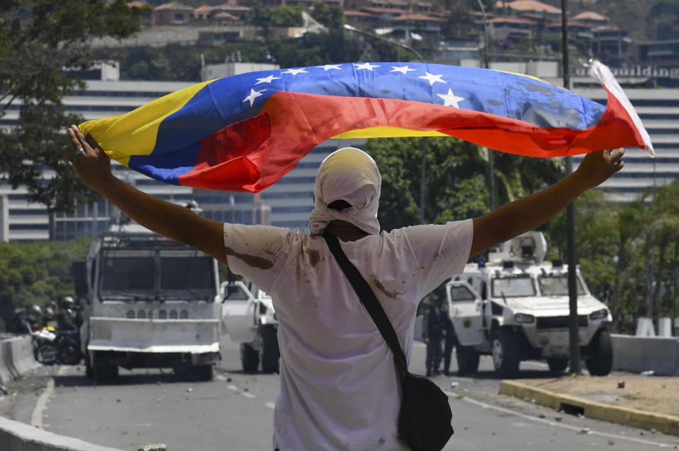 Un simpatizante del líder opositor Juan Guaidó despliega una bandera de Venezuela durante enfrentamientos con fuerzas leales al presidente Nicolás Maduro durante un alzamiento militar fallido en Caracas, el 30 de abril de 2019 (AFP | Yuri CORTEZ)