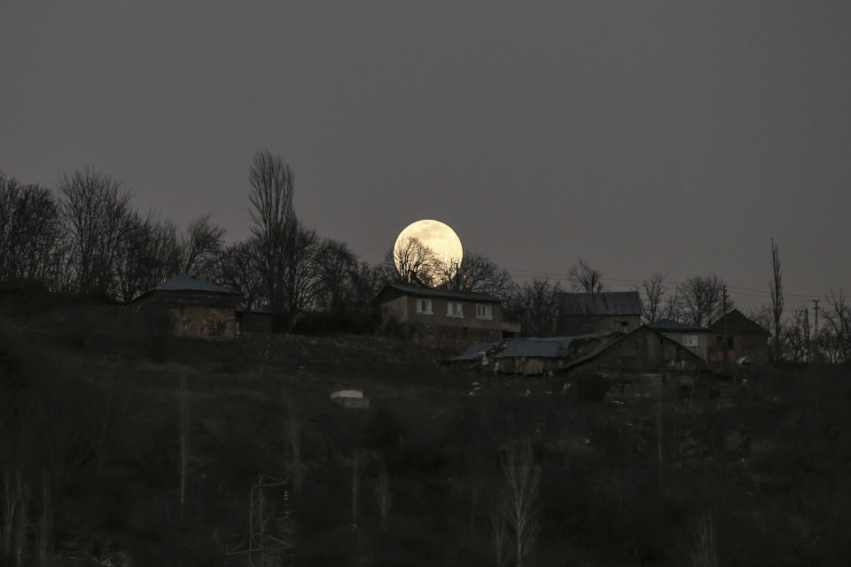 A full moon rises over the isolated village of Gumuslu in the district of Sivas, central Turkey, Friday, Feb. 26, 2021. Vaccination teams in Turkey have been reaching isolated mountain villages in Turkey’s central Sivas province as the government aims to inoculate 60% of the country’s population against the coronavirus over the next three months. (AP Photo/Emrah Gurel)