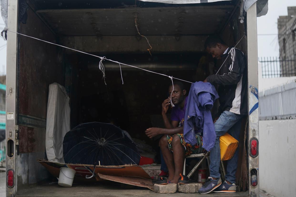 Earthquake-displaced people sit inside a container for protection from the elements the morning after Tropical Storm Grace swept over Les Cayes, Haiti, Tuesday, Aug. 17, 2021, three days after a 7.2-magnitude earthquake.