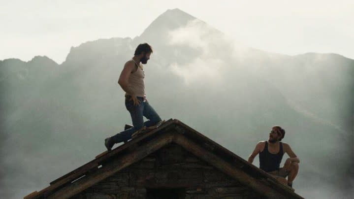 A man looks down at another man on a mountain in The Eight Mountains.