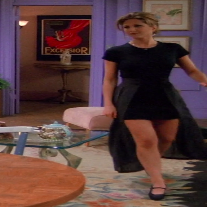 Rachel wearing a short-sleeve shirt and a miniskirt with an attached cape