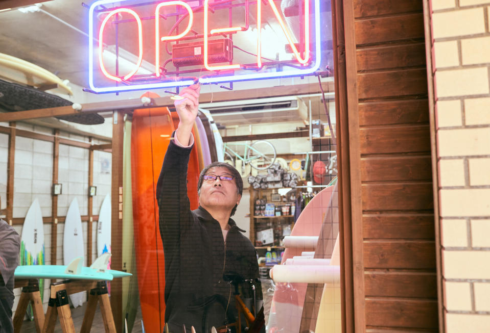 Shop owner turning on an "open" neon sign