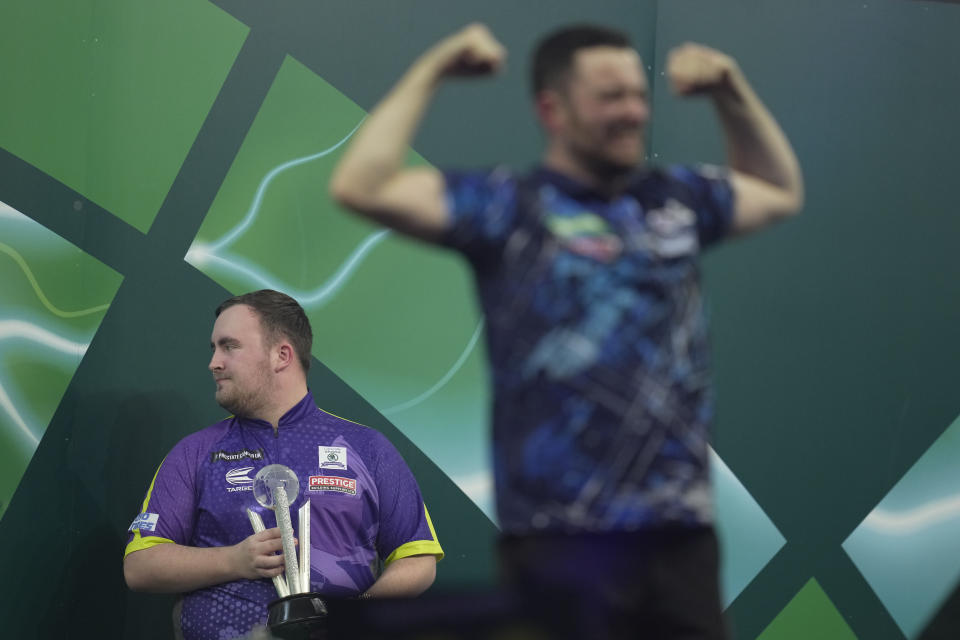 Luke Littler of England, who holds the runner-up trophy, looks away as Luke Humphries of England celebrates after winning the final match against at the World Darts Championship, at Alexandra Palace in London, Wednesday, Jan. 3, 2024. (AP Photo/Kin Cheung)