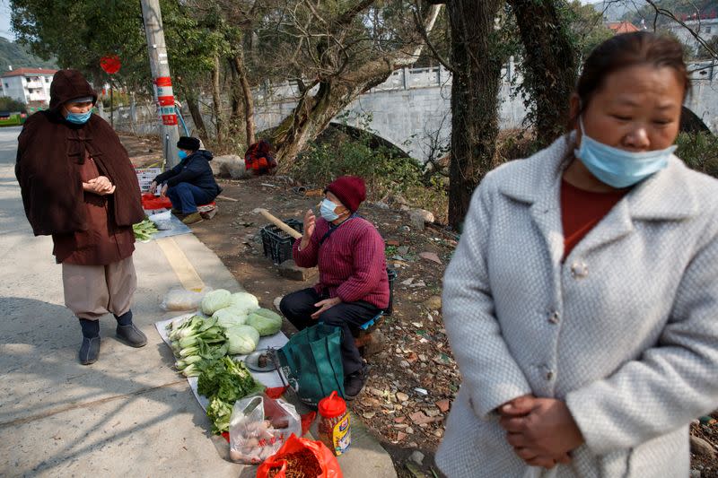 People wear face masks in a village outside Donglin Temple that is under lockdown because of the coronavirus outbreak in Jiujiang