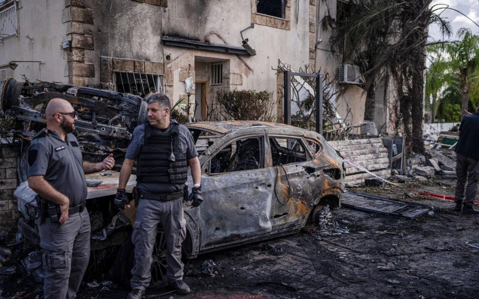 Security forces investigate a damaged vehicle