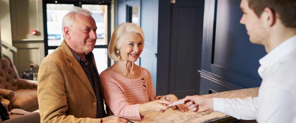 Senior Couple Checking In At Hotel Reception