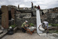 Volunteers clear rubble on the ground floor of Zhanna and Serhiy Dynaeva's house which was destroyed by Russian bombardment, in the village of Novoselivka, near Chernihiv, Ukraine, Saturday, Aug. 13, 2022. Residents in many heavily-damaged areas in Ukraine have set up their own initiatives to rebuild homes before the winter as international organizations rush aid to Ukraine to help with the reconstruction effort. (AP Photo/Evgeniy Maloletka)