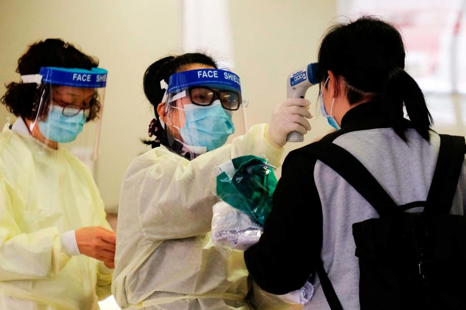 A medical worker takes the temperature of a woman in the reception of Queen Elizabeth Hospital in Hong Kong (REUTERS)