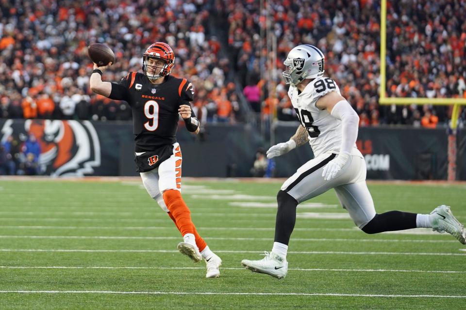 Cincinnati Bengals quarterback Joe Burrow (9) throws while being pressured by Las Vegas Raiders' Maxx Crosby (98) during the first half of an NFL wild-card playoff football game, Saturday, Jan. 15, 2022, in Cincinnati. (AP Photo/Jeff Dean)