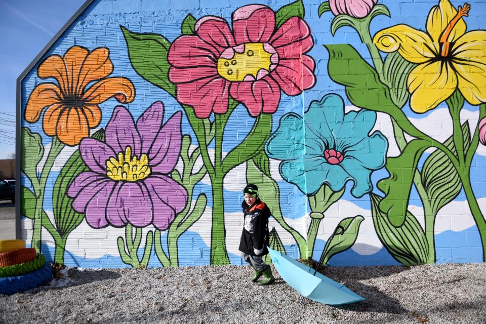 Scott Gamble, 5, of Louisville is surrounded by flowers on a frosty winter day at Umbrella Alley in Louisville.  Wednesday, December 21, 2022.