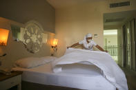 A hotel employee wearing a protective face mask prepares a room, in Antalya, southern Turkey, Saturday, June 19, 2021. Hotels in Turkey's Antalya region, a destination beloved by holidaymakers, are preparing to finally resume operations as they expect the return of international tourists after months of setbacks caused by the pandemic that halted travel. (AP Photo/Emrah Gurel)