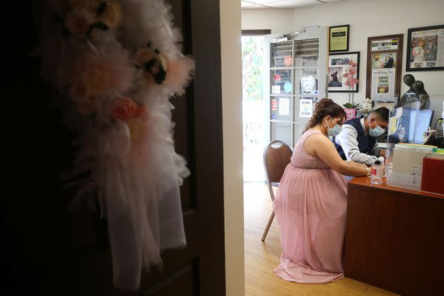 <p>Mario Tama/Getty </p> Clarissa and Luis Romero fill out paperwork before their wedding ceremony at Cute Little Wedding Chapel on February 14, 2021