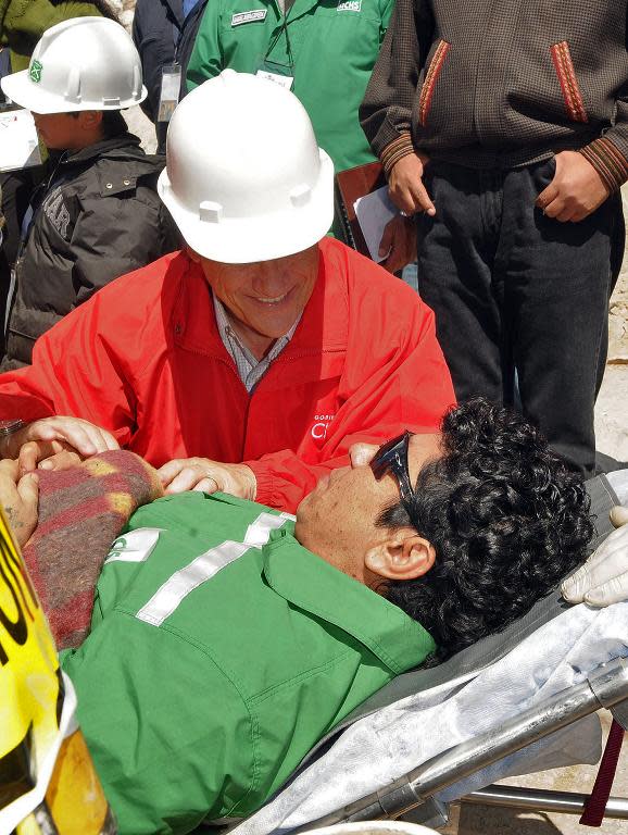 A picture released by Chile's presidential press office shows miner Victor Zamora speaking with President Sebastian Pinera as he is taken to the field hospital near Copiapo on October 13, 2010