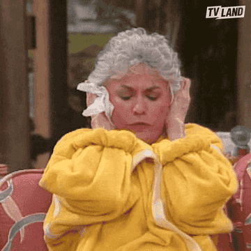 Dorothy Zbornak from The Golden Girls sits in a robe on a couch, covering her ears.