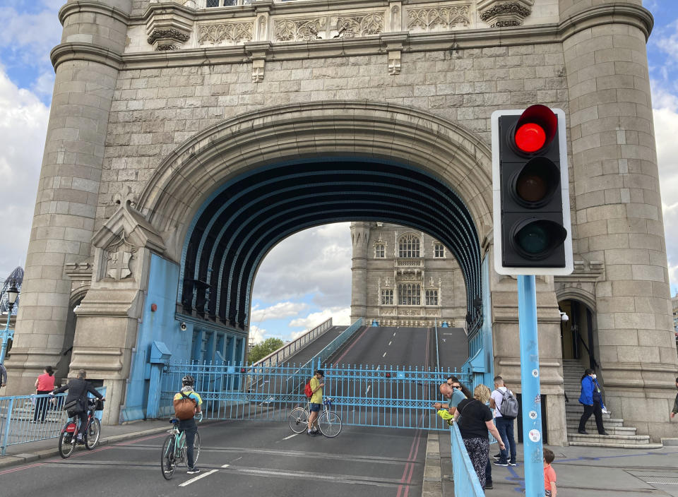 Tower Bridge crossing the River Thames is stuck open, leaving traffic in chaos and onlookers stunned as the iconic river crossing remains open, in London, Saturday Aug. 22, 2020. The historic bridge has failed to close Saturday after opening to allow ships to pass underneath on the River Thames. (AP Photo / Tony Hicks)