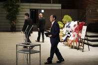 Japanese Prime Minister Yoshihide Suga walks to speak to media after a government task force meeting for the new virus measures, at the prime minister's office Friday, April 9, 2021, in Tokyo. Japan announced Friday that it will raise the coronavirus alert level in Tokyo to allow tougher measures to curb the rapid spread of a more contagious variant ahead of the Summer Olympics. (AP Photo/Eugene Hoshiko, Pool)