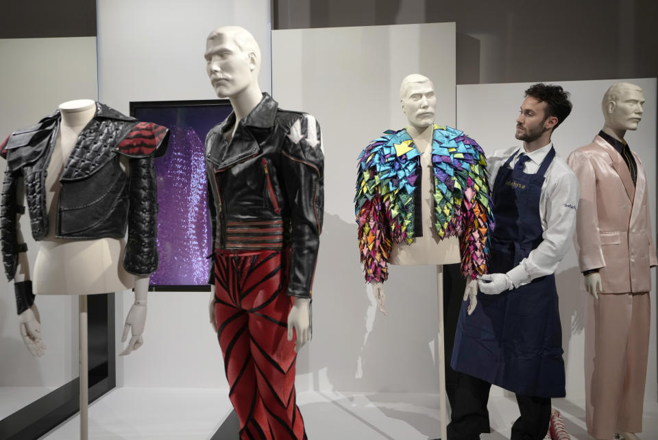 A Sotheby's handler displays a 'Rainbow Coloured Satin Arrow Applique Jacket from 1982' at Sotheby's auction rooms in London, Thursday, Aug. 3, 2023. More than 1,000 of Freddie Mercury's personal items, including his flamboyant stage costumes, handwritten drafts of "Bohemian Rhapsody" and the baby grand piano he used to compose Queen's greatest hits, are going on show in an exhibition at Sotheby's London ahead of their sale. (AP Photo/Kirsty Wigglesworth)