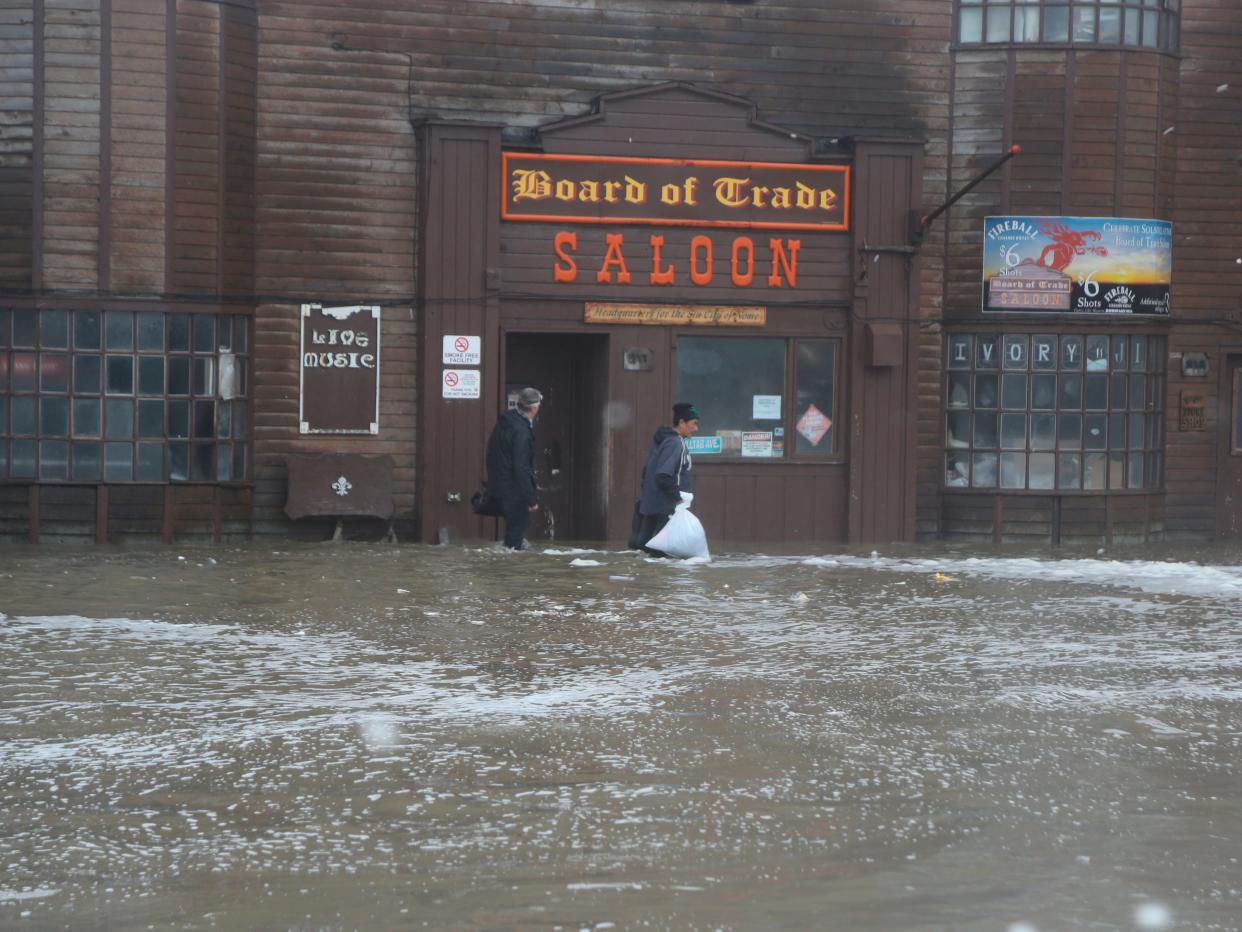 Two men walk through rushing water on Front Street, just a half block from the Bering Sea, in Nome, Alaska, on Saturday, Sept. 17, 2022. Much of Alaska's western coast could see flooding and high winds as the remnants of Typhoon Merbok moved into the Bering Sea region. The National Weather Service says some locations could experience the worst coastal flooding in 50 years.