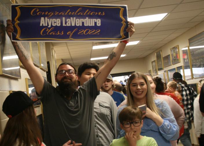 Andrew Wipf holds a sign congratulating his sister Alyce LaVerdure, who graduated from Central High School Sunday afternoon.