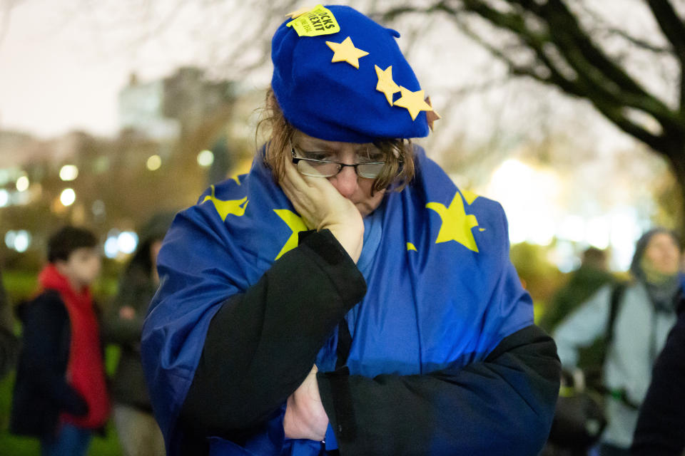 A woman holds her head in her hand during a candlelight vigil in support of remaining in the European Union in Cardiff