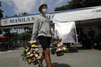 A man wearing a face mask to prevent the spread of the coronavirus carries flowers at the North Cemetery, Wednesday, Oct. 28, 2020, in Manila, Philippines. The government has ordered all private and public cemeteries, memorial parks, and columbariums to be closed from Oct. 29 to Nov. 4, 2020, to prevent people from gathering during the observance of the traditionally crowded All Saints Day and to help curb the spread of the coronavirus. (AP Photo/Aaron Favila)